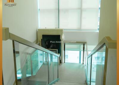 Interior view of a staircase with glass railings and large windows