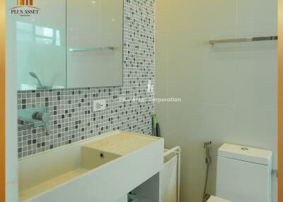 Modern bathroom with sink, cabinet, toilet, and mosaic wall tiles