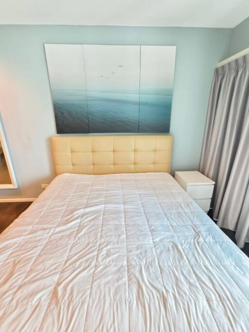 Bright bedroom with ocean artwork above a padded bed
