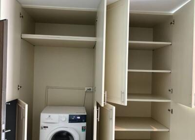 Compact laundry room with built-in storage and modern washing machine