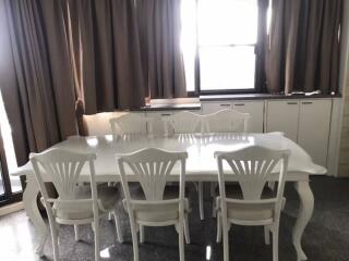 Elegant dining room with large white dining table and chairs, natural light from window