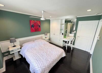Spacious bedroom with en-suite bathroom, green walls, and hardwood floors