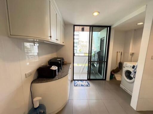 Modern kitchen with white cabinets, granite countertop, and access to balcony