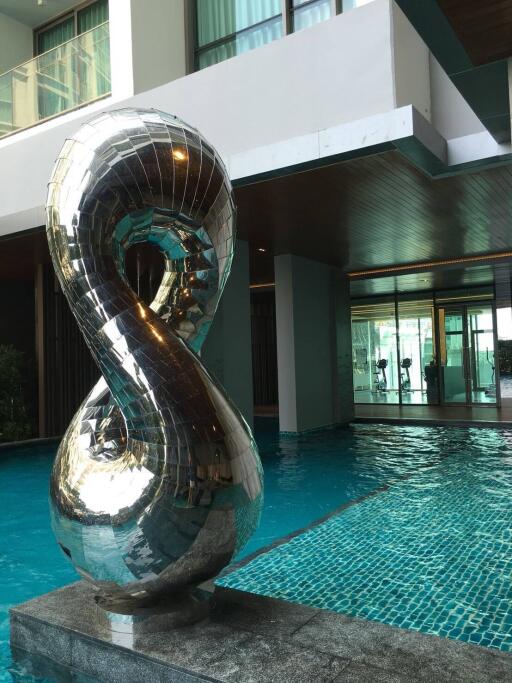 Elegant poolside with reflective sculpture in a modern residential building