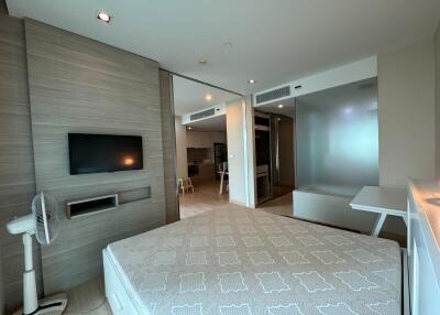 Spacious modern bedroom with mounted television and connected to other rooms