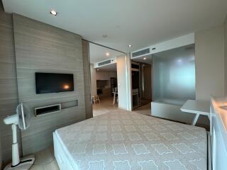 Spacious modern bedroom with mounted television and connected to other rooms