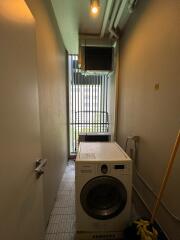 Narrow laundry area with washing machine and security grilles