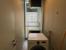 Narrow laundry area with washing machine and security grilles