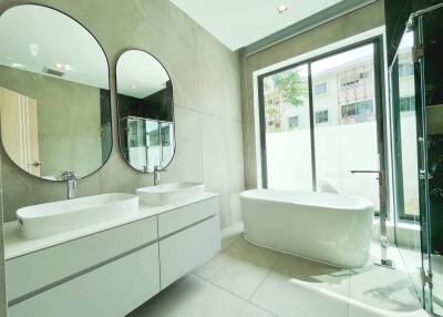 Modern spacious bathroom with large mirrors and freestanding tub