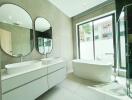 Modern spacious bathroom with large mirrors and freestanding tub