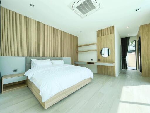 Modern minimalist bedroom with large bed and wooden accents