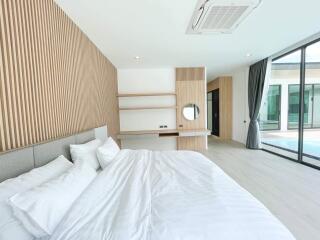 Spacious bedroom with modern wooden features and pool view