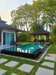 Luxurious backyard with a swimming pool, lush greenery, and a poolside gazebo