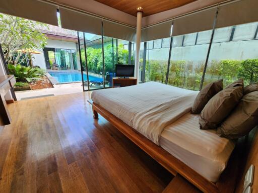 Spacious bedroom with pool view, large windows and wooden flooring