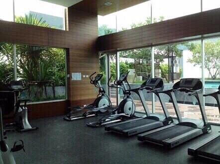 Modern gym with treadmills and exercise bikes overlooking a pool