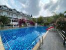 Luxury residential outdoor swimming pool with adjacent houses and lush garden