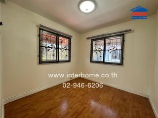 Spacious bedroom with large windows and hardwood floors