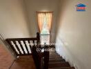 Elegant wooden staircase leading to a well-lit hallway with a stained glass window