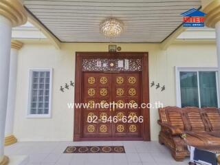 Elegant house entrance with ornate wooden door and chandelier