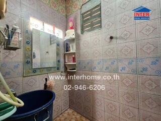 Small, tiled bathroom with storage shelves and mirror