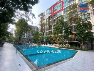 Modern residential building with an outdoor swimming pool surrounded by lush greenery