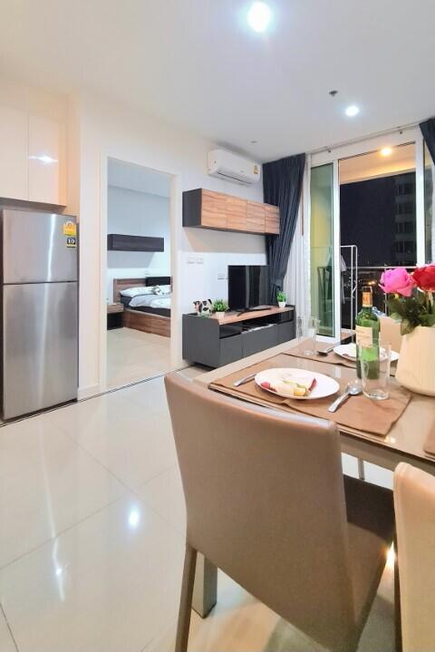 Modern apartment interior with open plan living space featuring kitchen, dining area, and bedroom
