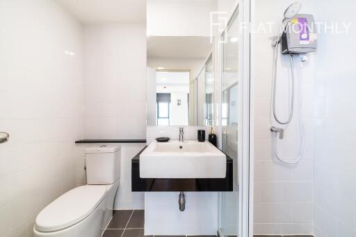 Modern bathroom with sleek design featuring a walk-in shower, white basin, and well-lit mirror