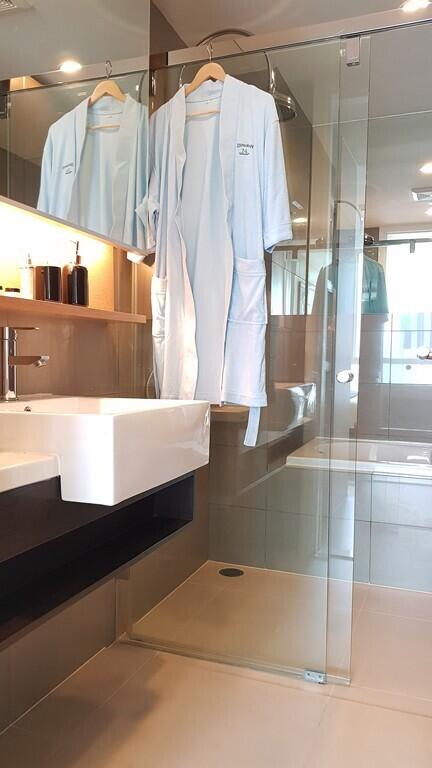 Modern bathroom interior with glass shower and twin bathrobes