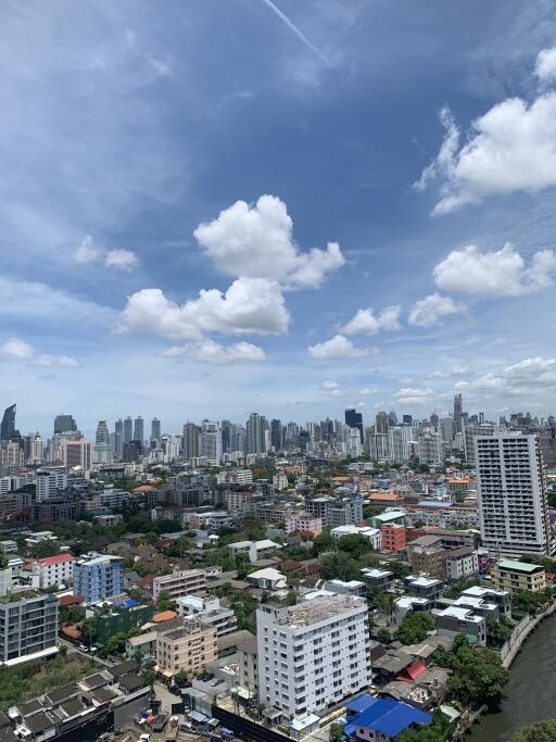 High-rise cityscape view showing residential and commercial buildings under a blue sky with clouds
