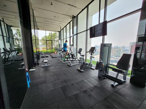 Modern gym within a high-rise building featuring large windows and city views