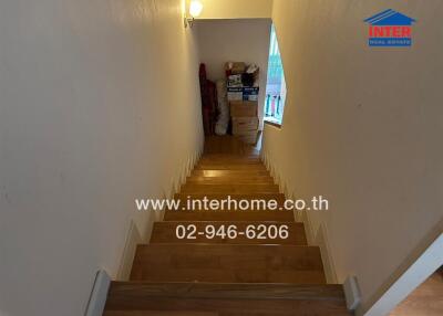 Interior view of a well-lit staircase descending into an entryway with visible storage space