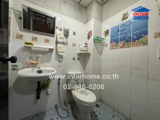 Compact and Fully Tiled Bathroom with Toilet and Sink