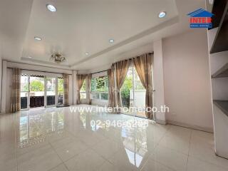 Spacious well-lit living room with large windows and glossy tiled flooring