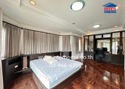 Spacious master bedroom with natural light and elegant wooden flooring