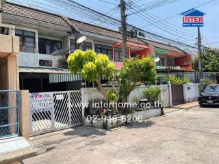 Exterior view of a residential townhouse with gated entrance and parked car