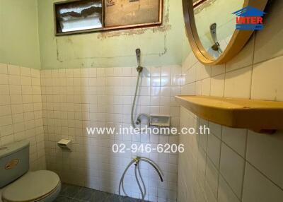 Compact bathroom with shower, tiled walls, and wooden shelf