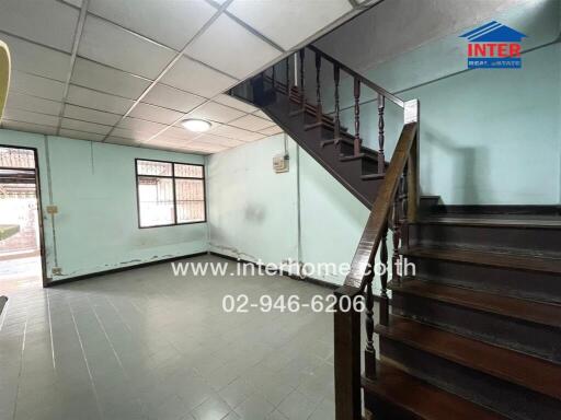 Spacious living area with wooden staircase and tiled flooring