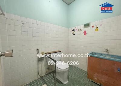 Spacious bathroom with white tiling and basic fixtures