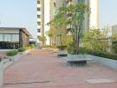 Spacious outdoor common area with seating and greenery between residential buildings