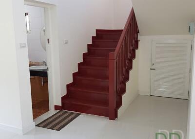 Bright building entrance with red staircase and access to multiple rooms