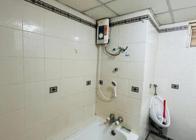 Brightly lit bathroom with modern amenities including a bathtub and wall-mounted water heater
