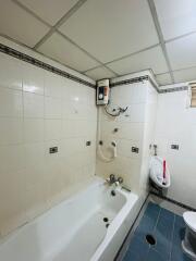 Brightly lit bathroom with modern amenities including a bathtub and wall-mounted water heater