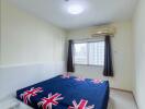 Compact bedroom with a British flag-themed bedding, air conditioner, and natural light