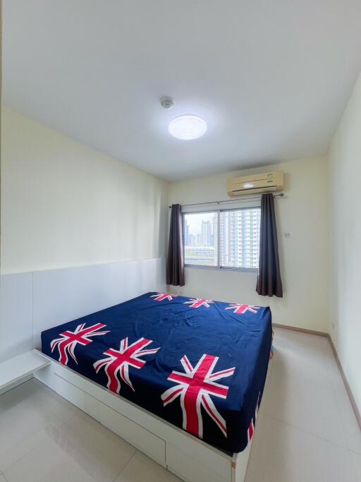 Compact bedroom with a British flag-themed bedding, air conditioner, and natural light