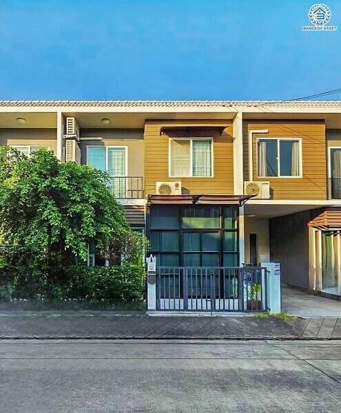 Exterior view of a modern two-story townhouse with yellow walls and elegant facade details