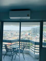 Spacious balcony with city view, including outdoor furniture and air conditioning unit