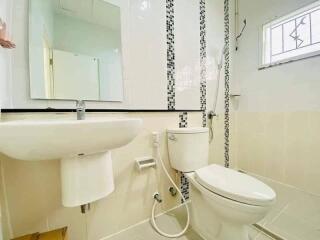 Modern bathroom with white ceramic fixtures and decorative mosaic tiles