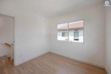 Spacious empty bedroom with hardwood floors and large window