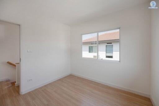 Spacious empty bedroom with hardwood floors and large window