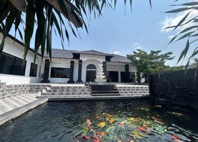 Luxurious home exterior with koi pond and steps leading to a grand entrance